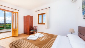 Een slaapkamer met een bed, een stoel, een kledingkast, een raam en uitzicht op de omgeving.