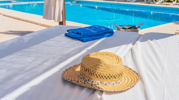 A poolside area with a sunbed, a straw hat, and a blue towel. - Holiday Home 'Finca Can Xet' with Mountain View, Pool & Wi-Fi (Felanitx)