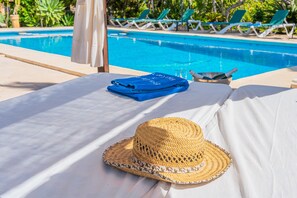 A poolside area with a sunbed, a straw hat, and a blue towel. - Holiday Home 'Finca Can Xet' with Mountain View, Pool & Wi-Fi (Felanitx)
