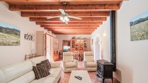 A living room with a sofa, two armchairs, a coffee table, a fireplace, and a ceiling fan. - Holiday Home 'Finca Can Xet' with Mountain View, Pool & Wi-Fi (Felanitx)