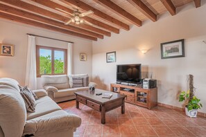 A living room with a sofa, coffee table, TV, wooden cabinet, and a ceiling fan.