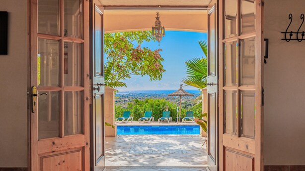An open doorway leading to a pool area with a view of the landscape.