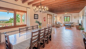 A dining area with a wooden table and chairs, a chandelier, and a view of the outdoors.