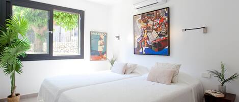 A hotel room with two beds, a large window, and a ceiling fan.