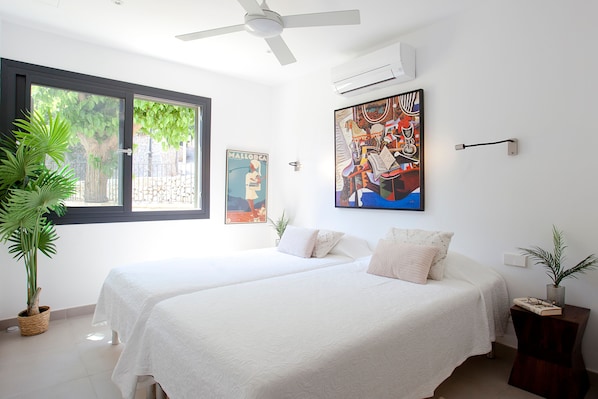 Une chambre d’hôtel avec deux lits, une grande fenêtre et un ventilateur de plafond.