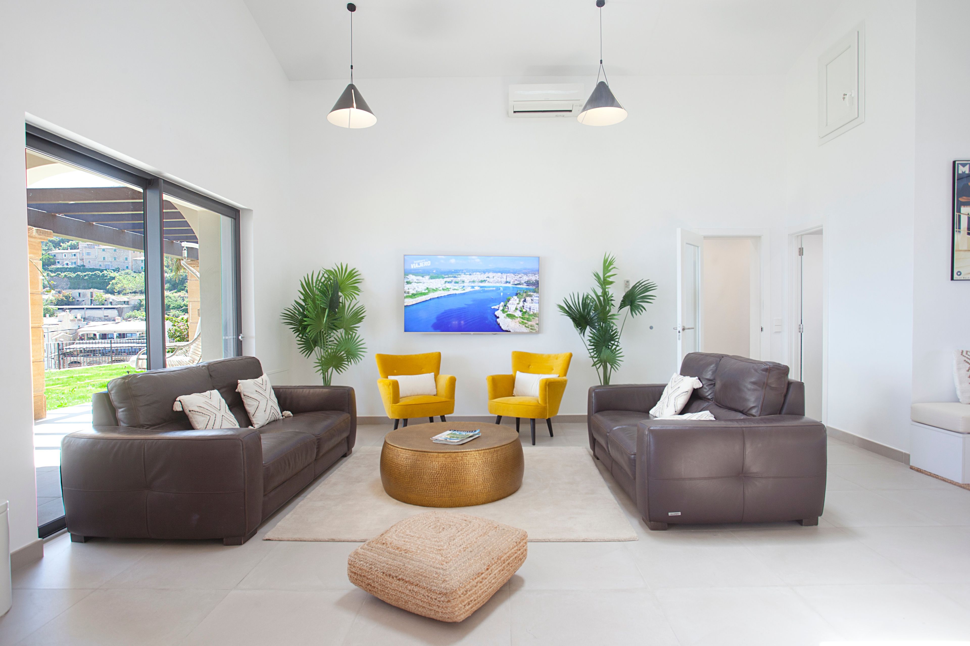 Una sala de estar moderna con dos sofás, una mesa de centro y dos sillones. Una ventana grande ofrece vistas a la costa.