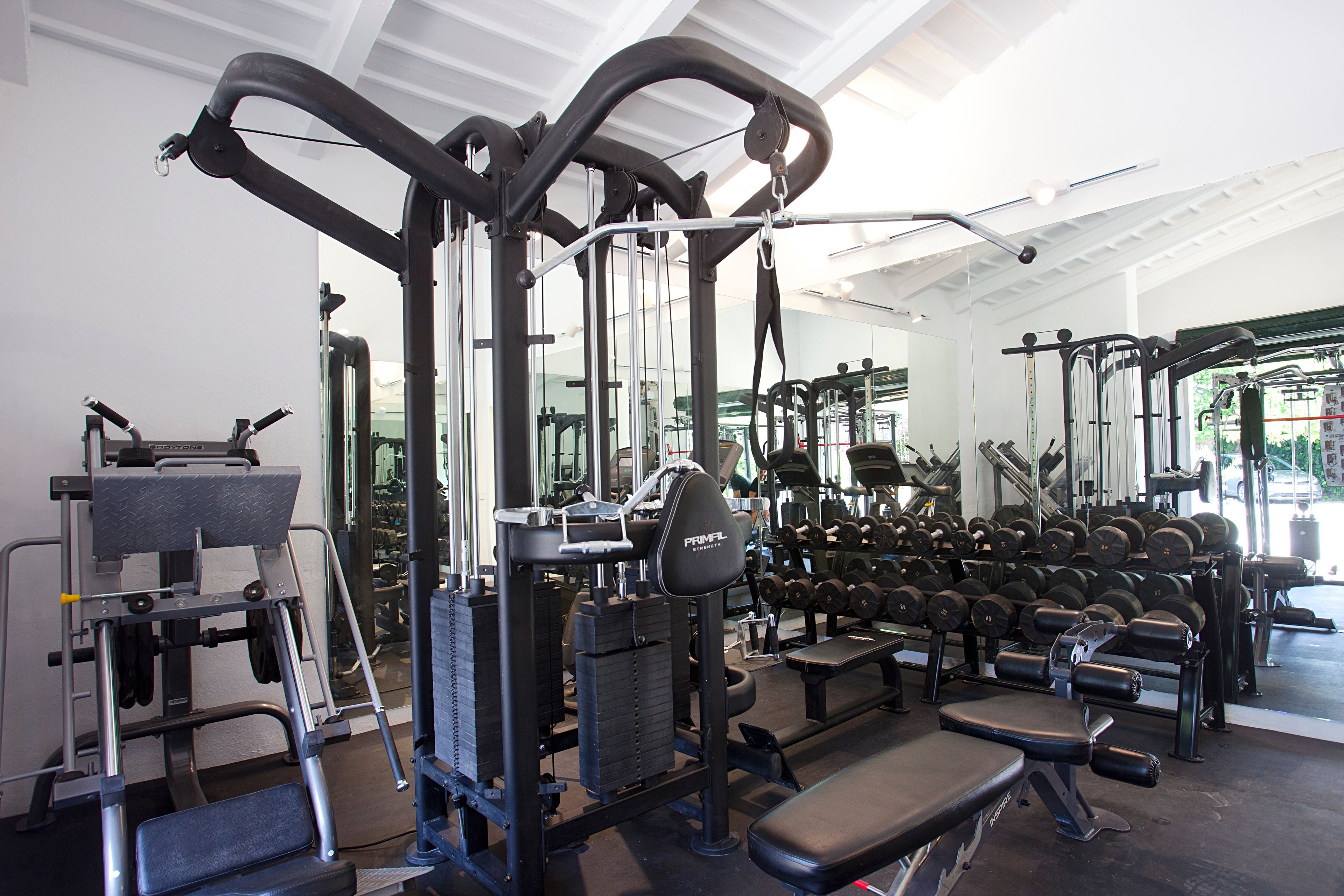 Un gimnasio con diversos equipos de ejercicio, incluyendo mancuernas y bancos.