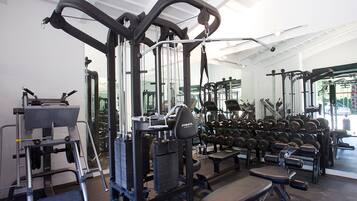Un gimnasio con diversos equipos de ejercicio, incluyendo mancuernas y bancos.