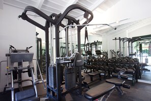 Une salle de sport équipée de divers appareils d’exercice, notamment des haltères et des bancs.