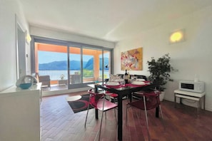 A dining area with a table set for four, a potted plant, and a view of mountains through large windows. - Gaeta 'lake View' (San Siro)