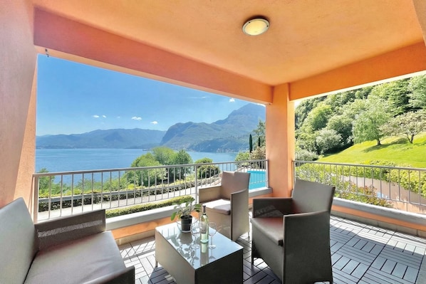 A balcony with a table, chairs, and a view of a lake and mountains. - Gaeta 'lake View' (San Siro)