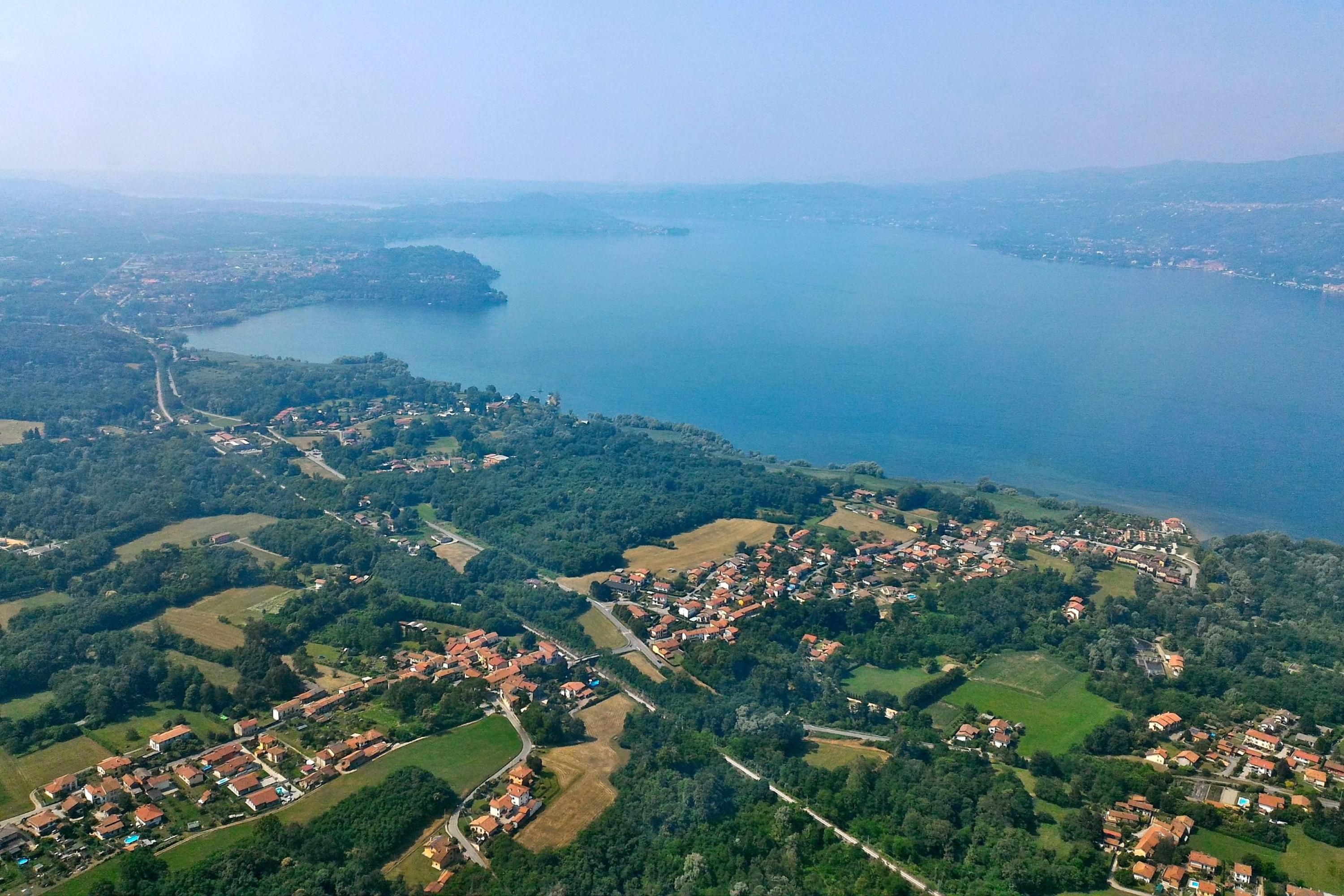 An aerial view of a coastal town with a mix of residential areas and open fields, surrounded by water and hills.