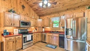 A kitchen with wooden cabinets, stainless steel appliances, and a ceiling fan. - Cozy Roughriver Lakefront Cabin (McDaniels)