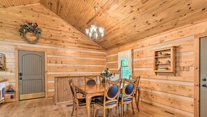 A wooden interior with a dining table and chairs, a chandelier, and a shelf with dishes. - Cozy Roughriver Lakefront Cabin (McDaniels)