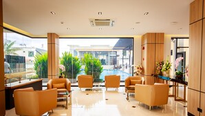 A modern hotel lobby with a glass wall, a pool view, and a reception desk. - Siri Hotel Lumphun (Lamphun)