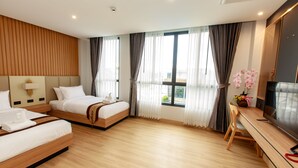 A hotel room with two beds, a desk, and a TV. - Siri Hotel Lumphun (Lamphun)