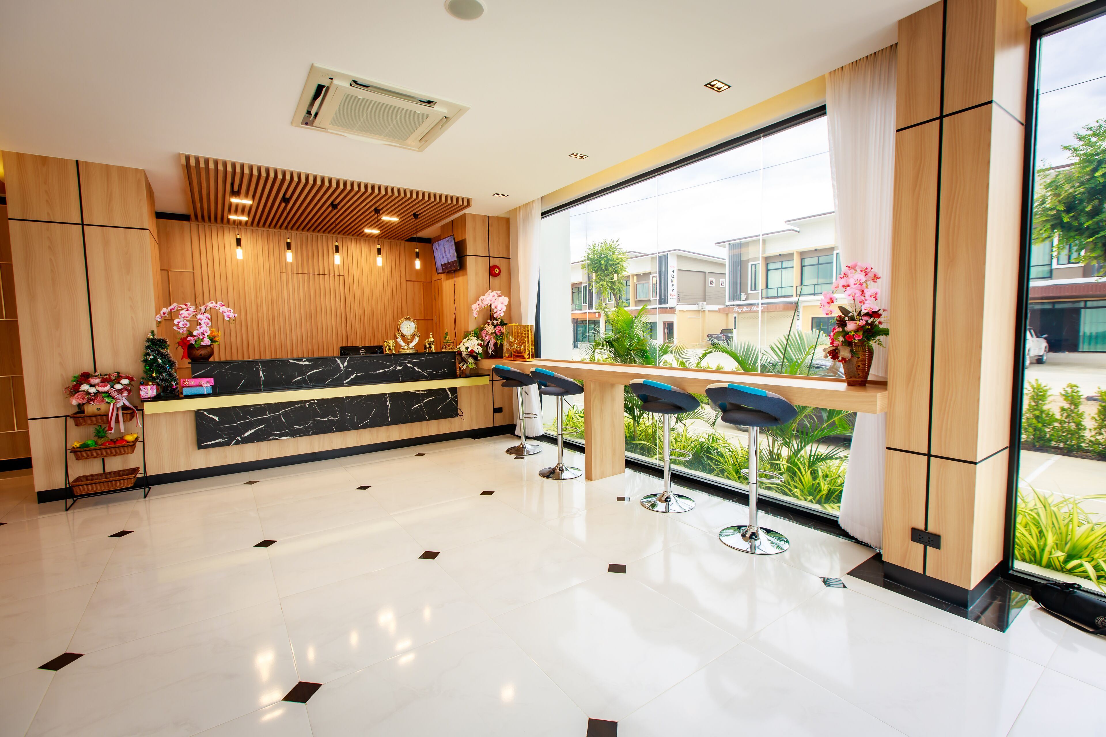 A modern reception area with a marble counter, wooden paneling, and a view of greenery outside.