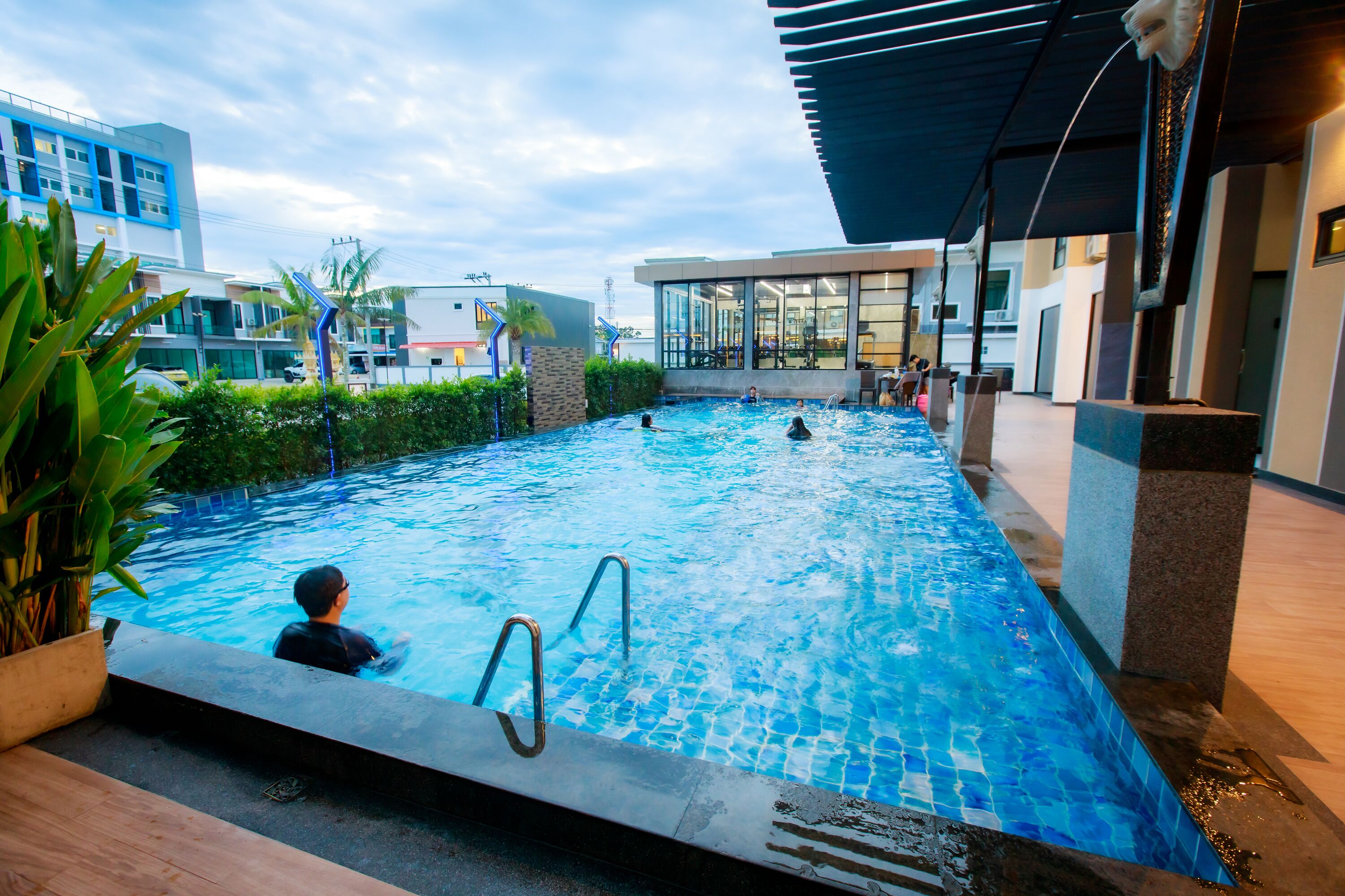 An indoor swimming pool with clear water, surrounded by modern architecture and a covered area.
