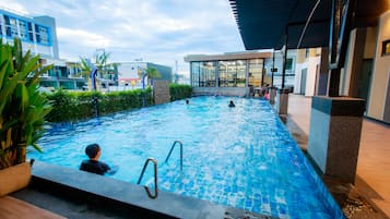 An indoor swimming pool with clear water, surrounded by modern architecture and a covered area.