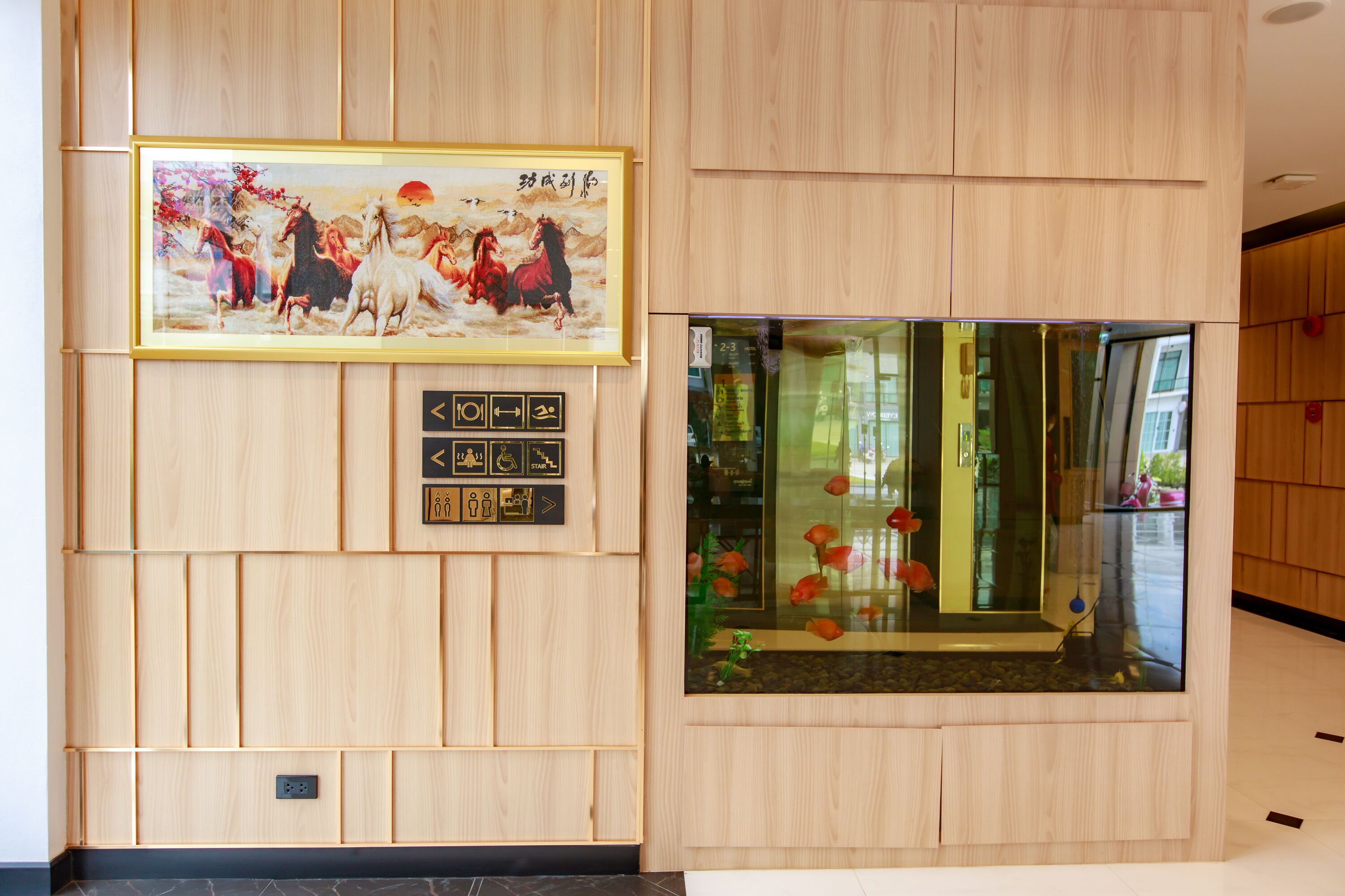 A wall with a framed painting, a fish tank, and a set of directional signs.