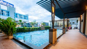 A swimming pool with a wooden deck, surrounded by potted plants and a covered seating area. - Siri Hotel Lumphun (Lamphun)