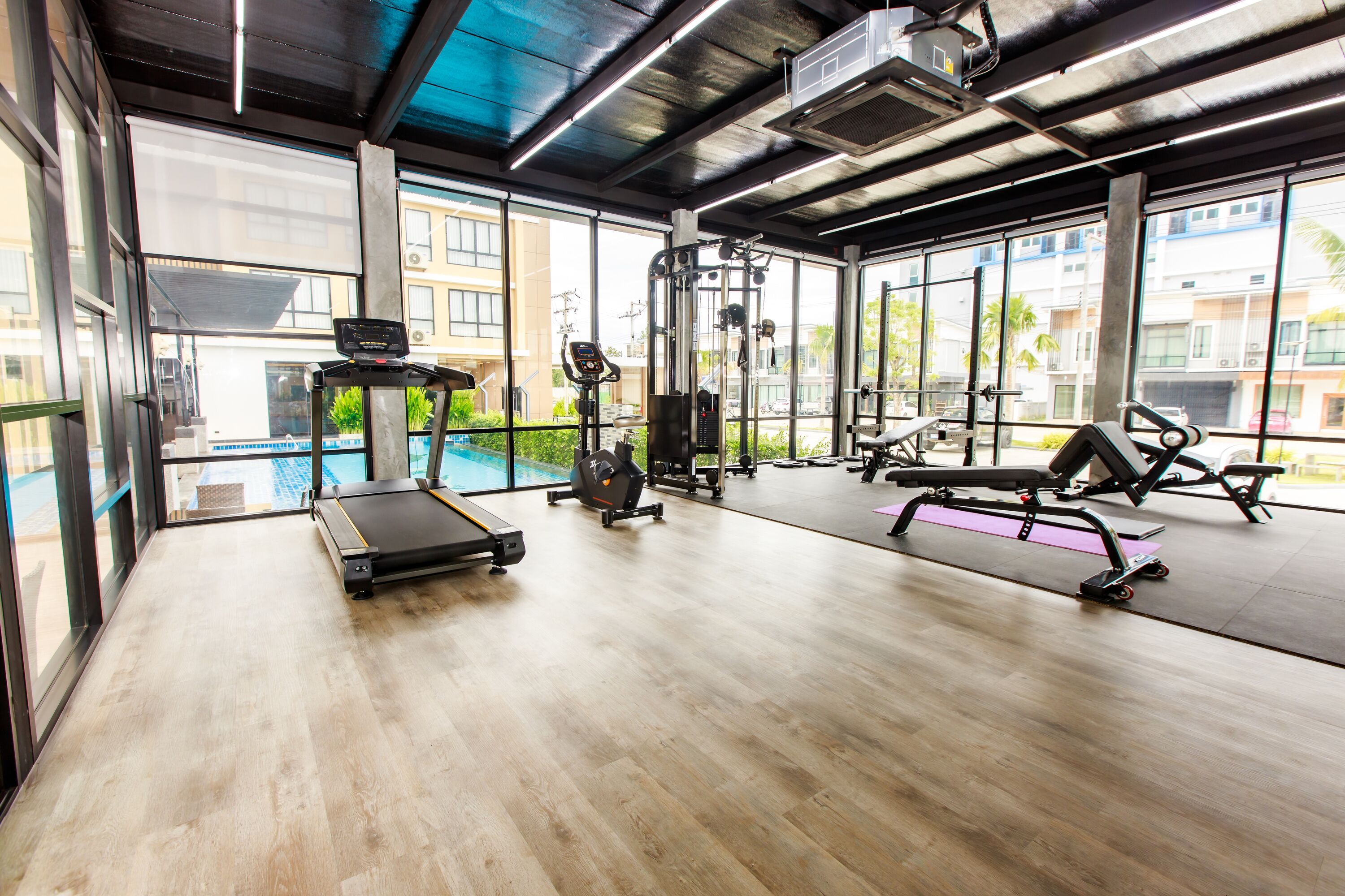 Un gimnasio con cinta de correr, máquinas de pesas y una máquina de remo.