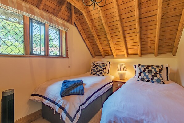 A bedroom with two beds, a window with a view, a lamp, and a heater.