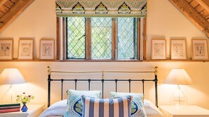 A bedroom with a bed, two bedside tables, a window with a decorative valance, and framed pictures on the wall. - The Gate House - sleeps 4 guests  in 2 bedrooms (Folkestone)