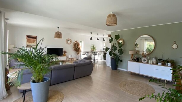 A spacious living area with a grey sofa, a dining table, and a kitchen in the background. - Modern villa with all comforts (Saint-Génies-des-Mourgues)
