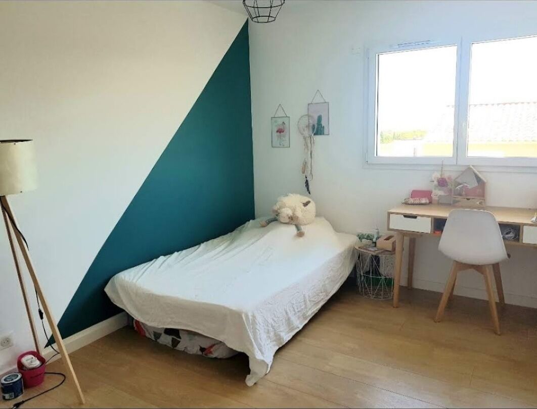 A bedroom with a bed, a desk, a chair, a lamp, and a window.