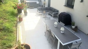 An outdoor patio with a dining table, chairs, a sofa, and a grill. - Modern villa with all comforts (Saint-Génies-des-Mourgues)