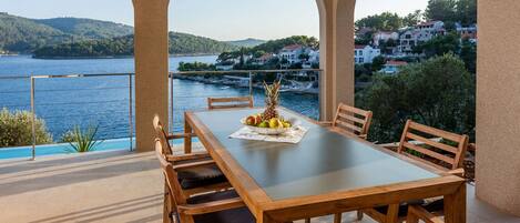 Una terraza con una mesa preparada para dos, con vistas a un lago y casas al fondo.