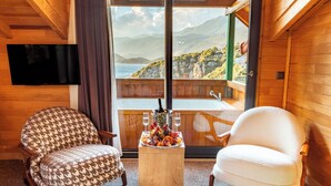A wooden interior with two armchairs, a small table with a fruit platter, and a TV mounted on the wall. - The Luxury Shelters (Kas)