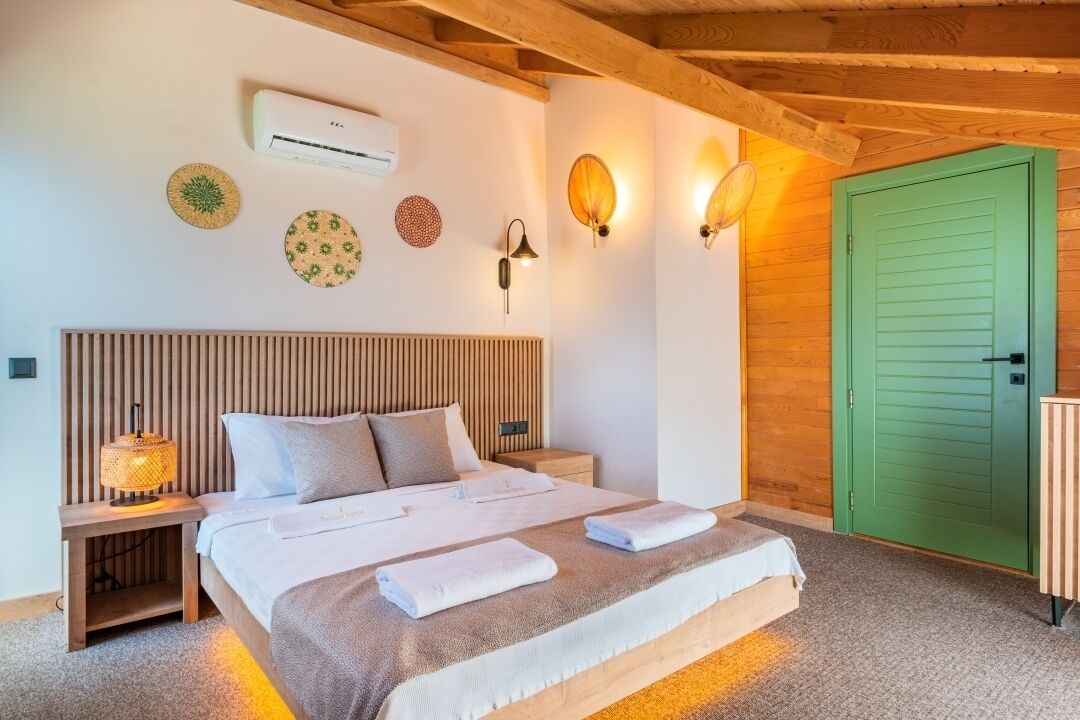 Un dormitorio ordenado con cabecera de madera, una puerta verde y aire acondicionado instalado en la pared.