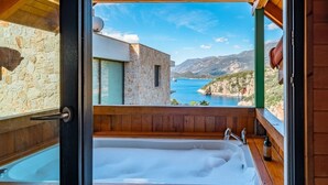 A room with a large bathtub and a view of a coastal landscape. - The Luxury Shelters (Kas)