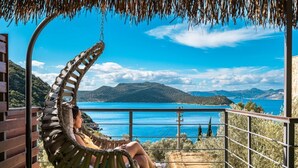 A hammock chair overlooking a scenic view of a body of water and mountains. - The Luxury Shelters (Kas)