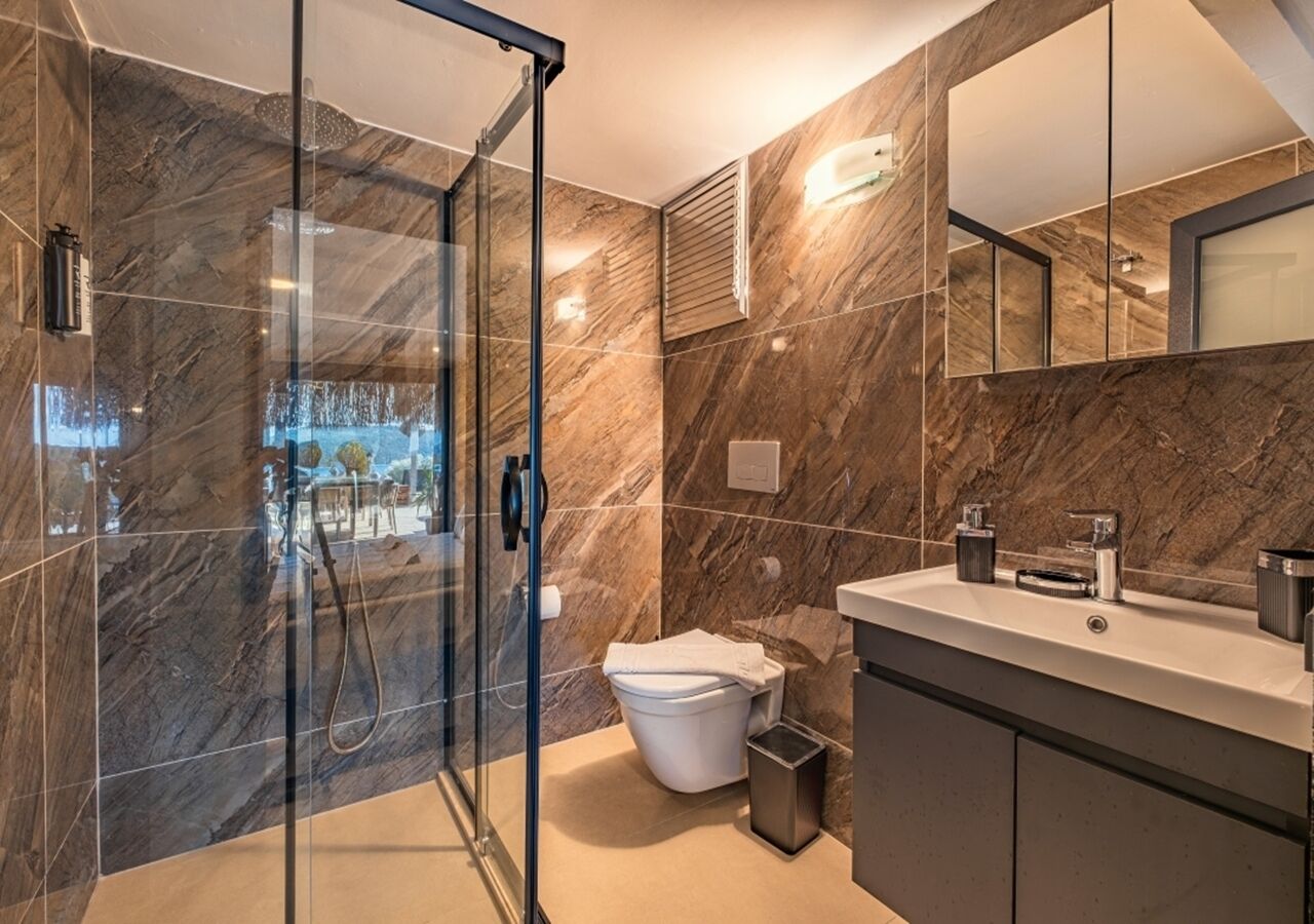 Une salle de bain moderne avec une douche à parois de verre, des toilettes et un meuble-lavabo avec un miroir.