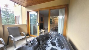A hot tub with a view of a house through a sliding glass door. - Snow Creek Village #49 (Sun Peaks)