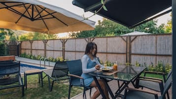 Eine Terrasse mit Tisch und Stühlen, ein Schwimmbad und eine Holzterrasse.