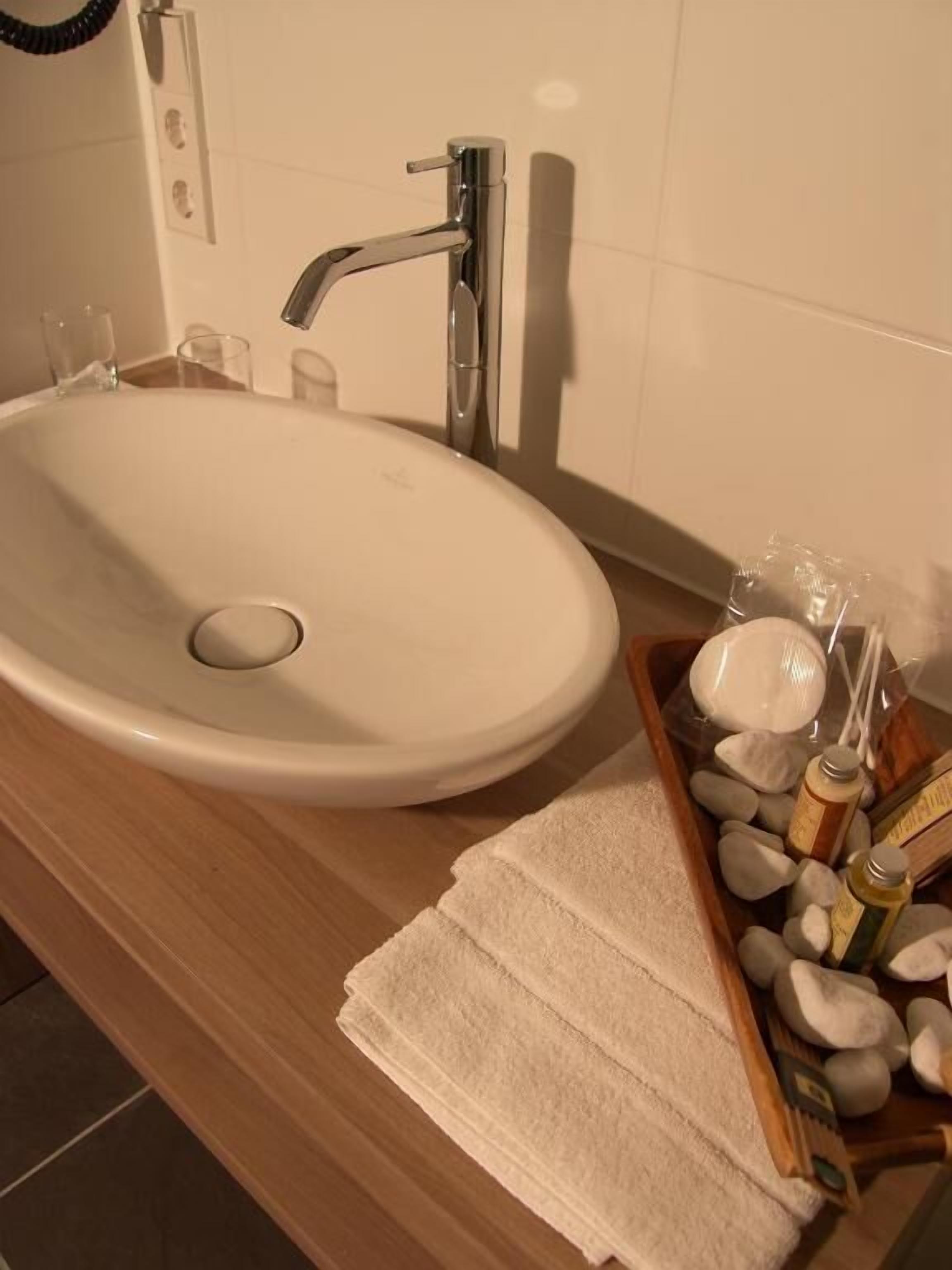A bathroom with a white sink, a wooden countertop, and a wooden tray holding toiletries.