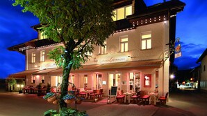A building with a restaurant named Löwen Strauss, featuring outdoor seating and a tree in front. - Alpin Lifestyle Hotel Löwen & Strauss (Oberstdorf)