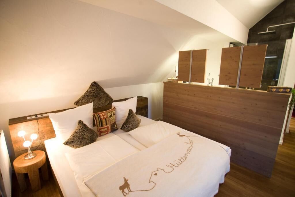 Ein Schlafzimmer mit hölzernem Kopfteil, einem Bett mit weißer Bettwäsche und einem Nachttisch mit Lampe.
