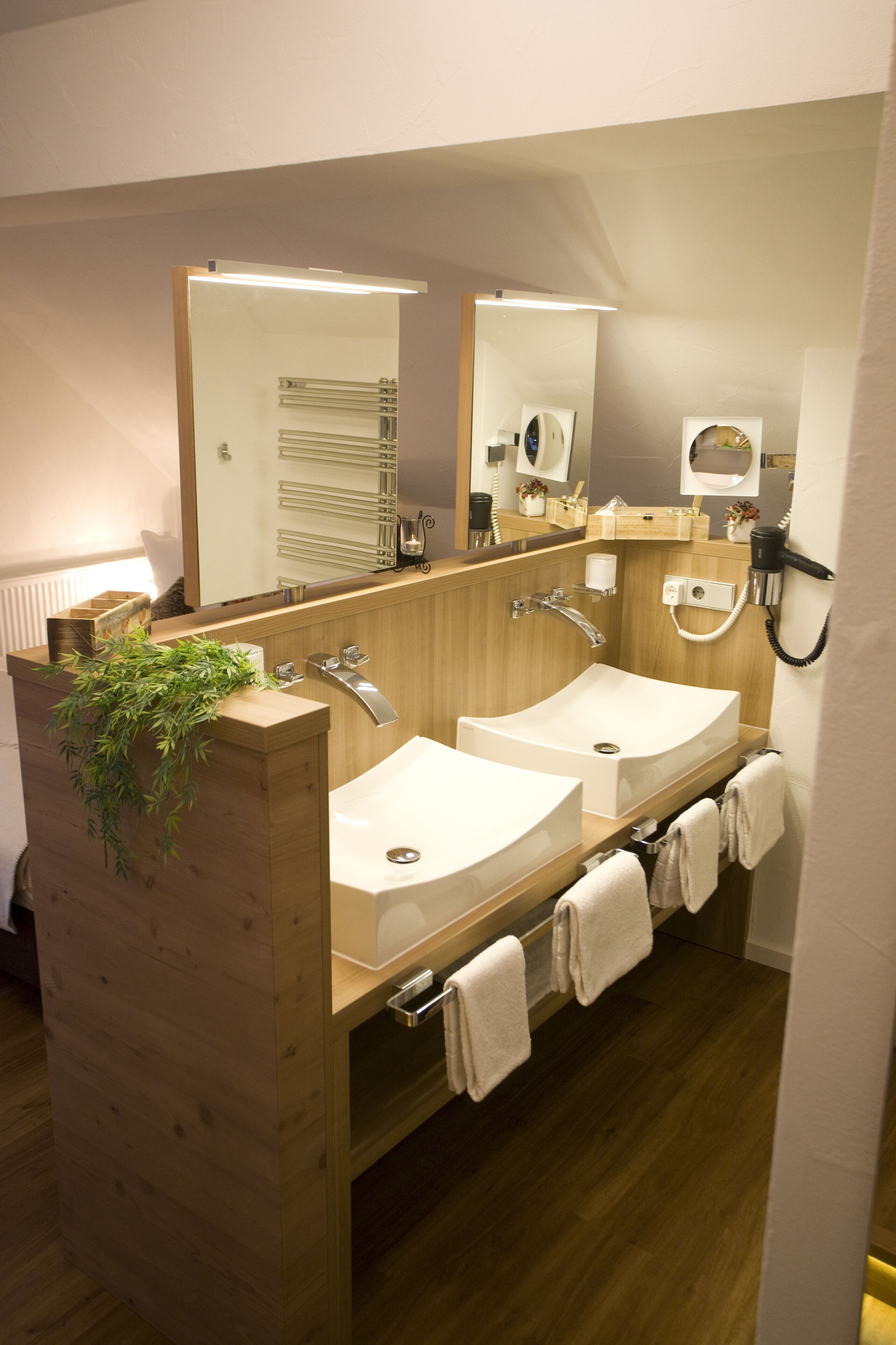 Un baño moderno con dos lavabos, un espejo, un perchero para toallas y un secador de pelo.
