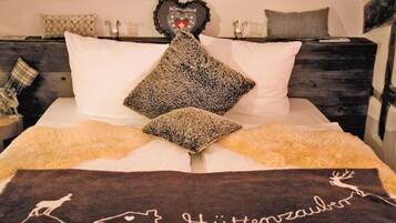 A bed with a patterned pillow, a heart-shaped decoration, and a towel with a deer design.