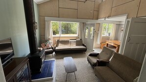 A spacious living room with a high ceiling, a built-in fireplace, a sofa, a coffee table, and a dining area with a wooden table.