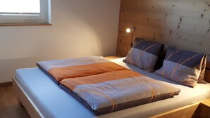 A bed with a wooden headboard, a bedside table, and a window.