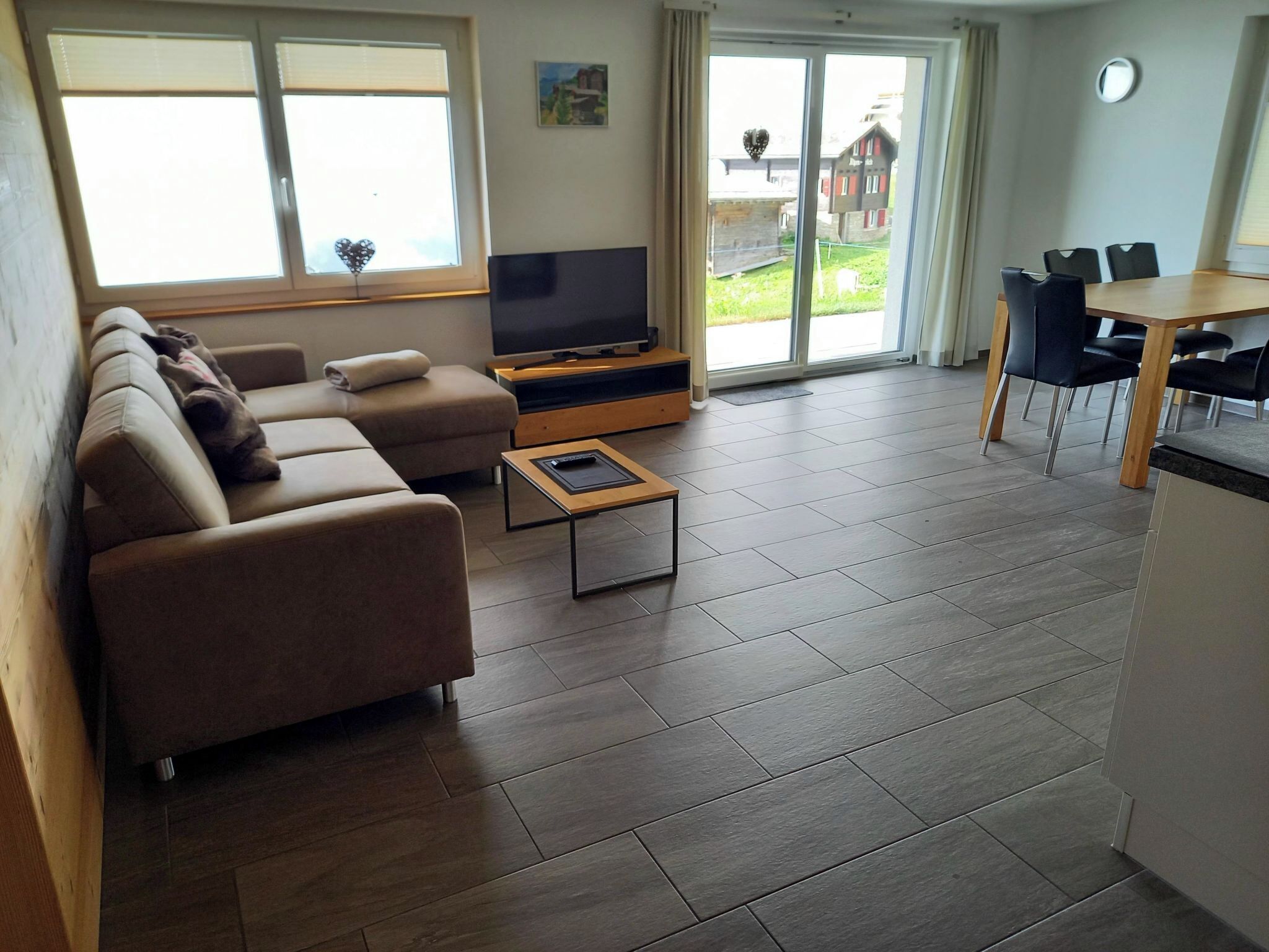 A living room with a sofa, TV, and a dining area with chairs and a table.