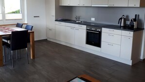 A modern kitchen with white cabinets, a black oven, and a dining area with a table and chairs.
