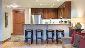A modern kitchen with wooden cabinets, stainless steel appliances, and a bar stool seating area. - Big Horn Lodge 409 Delightful slopeside Residence (Truckee)