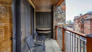 A balcony with outdoor seating, a stone wall, and a view of surrounding buildings. - Big Horn Lodge 409 Delightful slopeside Residence (Truckee)